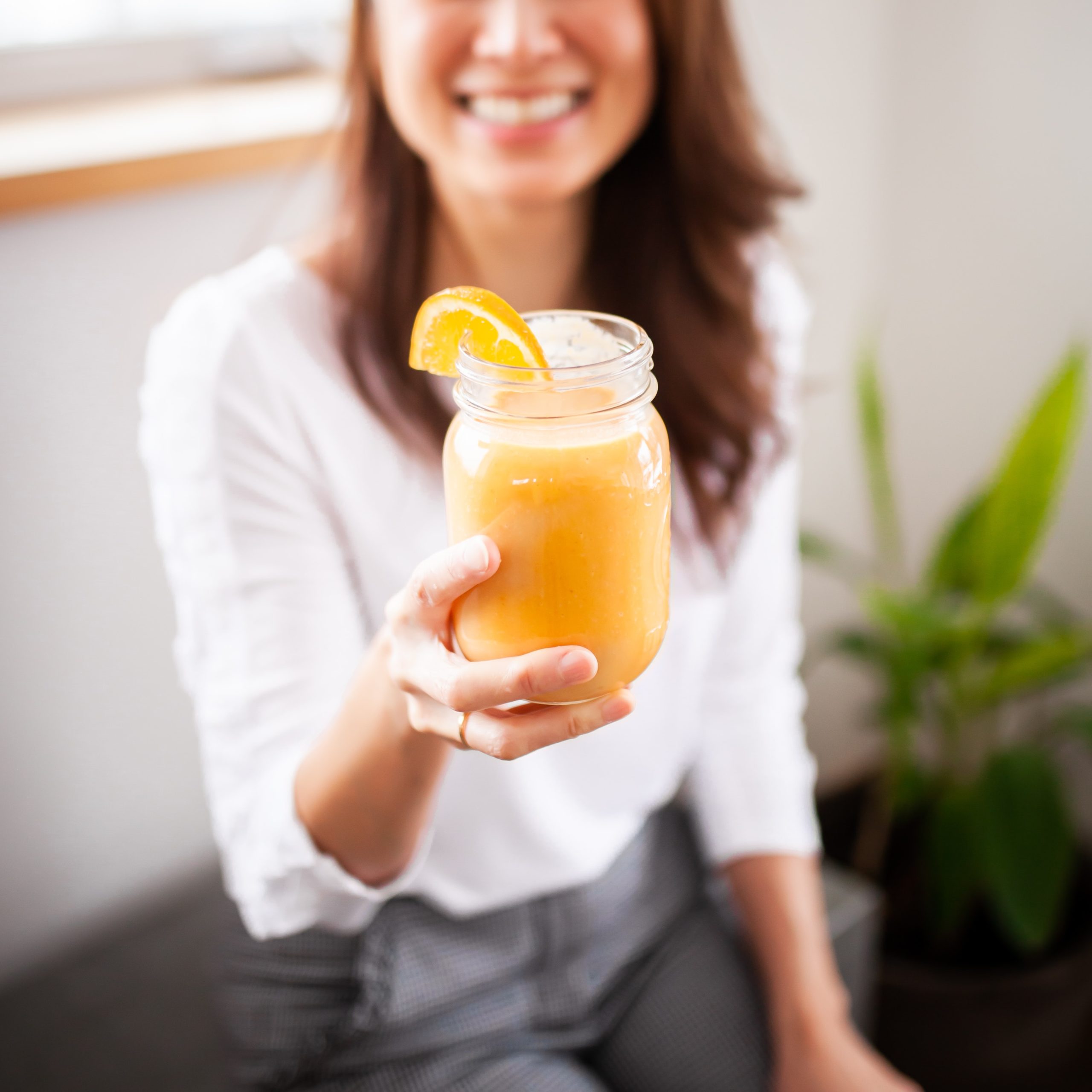 woman holding orange smoothie