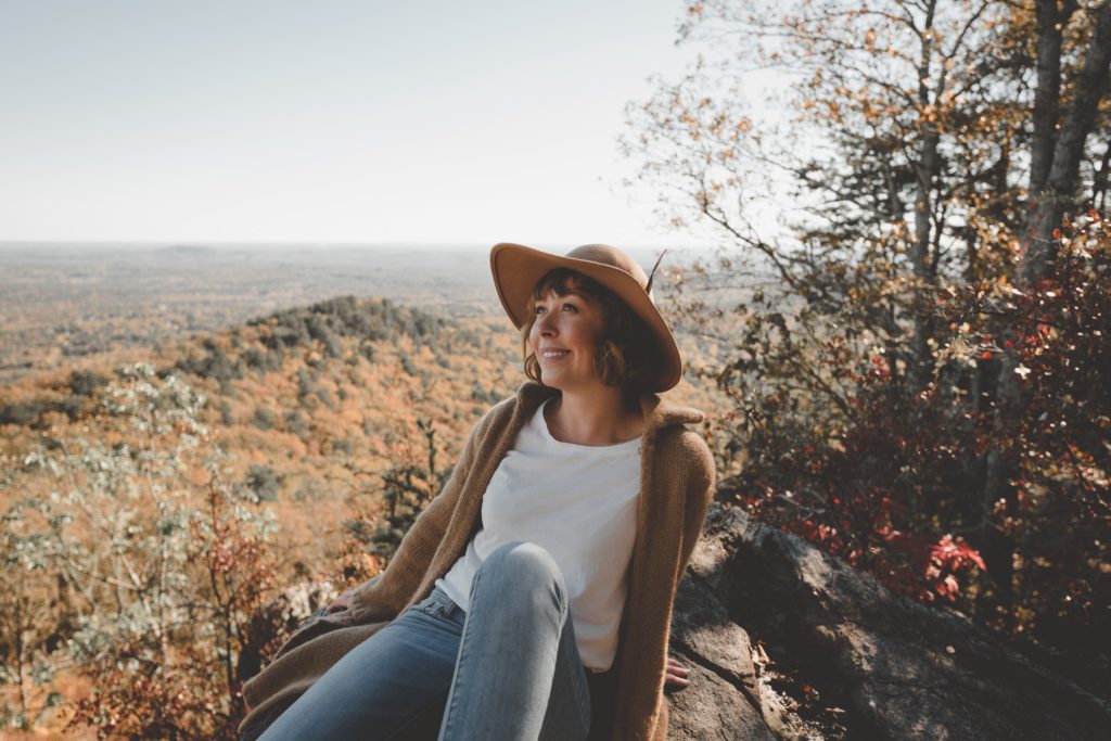 woman in hat sitting on a mountain