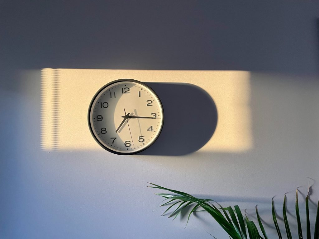 Clock on wall with time set for 7:15, sun setting from window, highlights importance of time for intermittent fasting window in support of weight loss