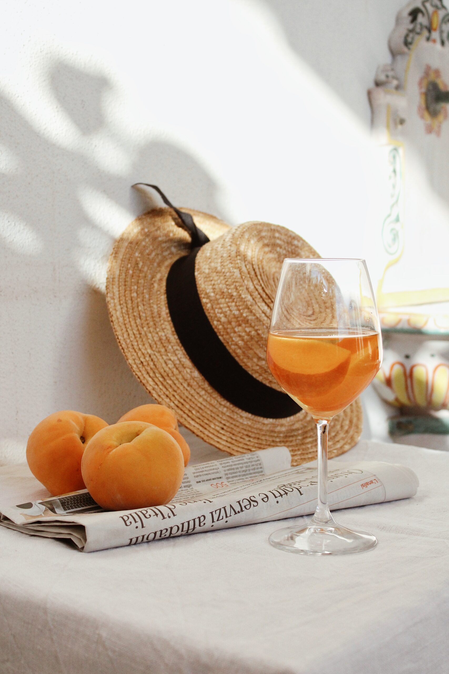 Apricots on newspaper with hat and refreshing spring drink in wine glass